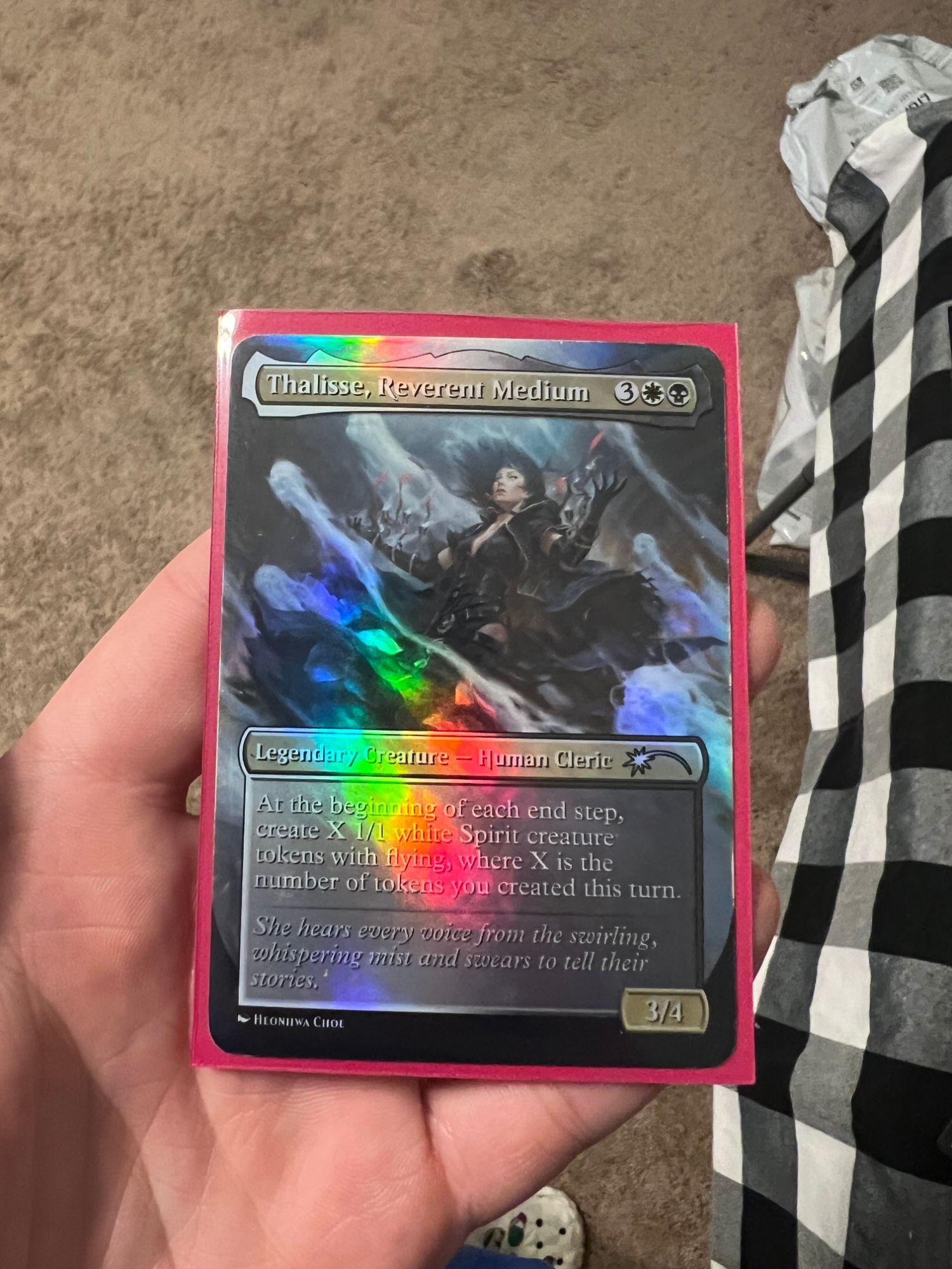 Holographic foil proxy of Thalisse, Reverent Medium, tilted in hand